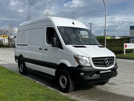 A 2017 Mercedes-Benz Sprinter van in white with black accents parked on a street featuring large wheels and a streamlined design