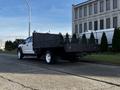 A 2018 Ford F-450 Super Duty truck with a flatbed and metal mesh sides parked on the street