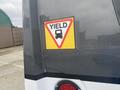 A sticker on a vehicle displaying a yield sign with a graphic of a truck inside the triangle