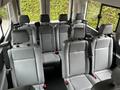 The interior of a 2017 Ford Transit 350 featuring multiple grey vinyl seats arranged in two rows with seat belts attached