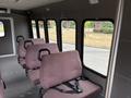 Interior of a 2014 Ford E-350 featuring several rows of brown seats with seat belts and large windows on one side