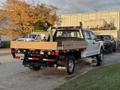 A 2018 Ford F-350 SD with a flatbed and wooden planks in the truck bed parked at a location with industrial elements in the background