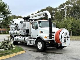 A white 2006 Sterling L7500 truck with a large vacuum tank and hoses attached to the rear for industrial cleaning operations