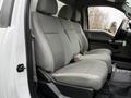 The interior of a 2017 Ford F-550 showing a row of gray fabric seats with a center console and armrest in a front cabin setting