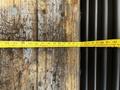 A measuring tape extends across a wooden surface with visible markings indicating measurements next to black cylindrical objects