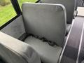 A gray bus seat with a safety belt attached visible in the foreground of the image