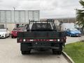 A 2020 Ford F-550 truck with a flatbed and a black mesh back is parked facing forward showcasing its tail lights and rear features