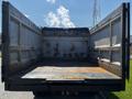 A 2016 Isuzu NPR truck with an open cargo bed showing a metal floor and sides that are slightly worn and stained from use