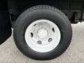 Close-up of a white metal wheel with a black tire mounted on a 2022 Isuzu NPR vehicle