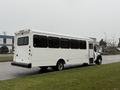 A white 2011 Ford F-550 bus with multiple windows parked on a grassy area