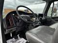 Interior view of a 2006 Freightliner M2 112 cab featuring a grey vinyl driver's seat with a steering wheel and dashboard controls in the foreground