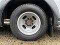 A close-up of a tire mounted on a 2015 Chevrolet Express featuring a silver wheel and a rugged tread design