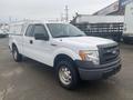 A white 2013 Ford F-150 with a cab and truck bed visible showcasing its front grille headlights and wheels