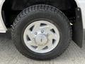 Close-up of a silver wheel with a shiny hubcap on a 2004 Ford Econoline featuring a rugged tire with the label OUTPOST AT
