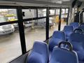 Interior view of a 2018 Chevrolet Express showing rows of blue upholstered seats and large windows with metal frames