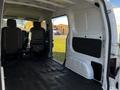 Interior view of a 2017 Nissan NV200 with two front seats visible and an open cargo area showing the flooring and walls