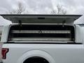 A 2017 Ford F-150 with an open truck bed cap revealing storage compartments and a ladder inside