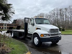 A 2008 Sterling Acterra truck with a flatbed design and bright orange lights on the roof parked on a paved area