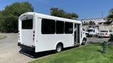 A white 2011 Chevrolet Express van with large windows and a ramp at the side is parked on the grass with its doors open