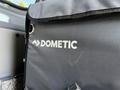 A black Dometic bag with a logo displayed prominently on the front, situated inside a vehicle.