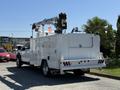 A 2024 Ford F-550 Super Duty truck with a white utility body and a mounted crane on the back