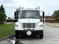 A white 2005 Freightliner M2 106 truck facing forward with its doors open and a diamond-shaped hitch in the center of the front bumper