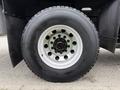 Close-up of a tire and wheel from a 2016 Peterbilt 348 featuring a shiny aluminum rim with multiple bolt holes and a thick rubber tire