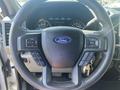 Interior view of a 2017 Ford F-150 steering wheel featuring controls for audio and cruise settings with the Ford logo prominently displayed in the center