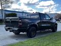 A black 2019 RAM 1500 pickup truck with a shiny finish and large wheels is parked with its rear facing the viewer