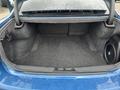 The trunk of a 2022 Dodge Charger is open showing a spacious interior with gray carpeting and a subwoofer on the left side