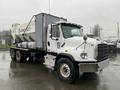 A 2020 Freightliner 114SD truck with a concrete mixer attachment in white and gray colors parked on a wet surface