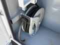 A reel with black hose coiled inside a compartment of a vehicle