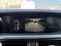 A rearview camera display showing the road behind a 2020 Alfa Romeo Stelvio with colored guidelines indicating distances