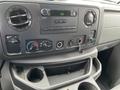 Dashboard of a 2009 Ford Econoline showing radio controls air conditioning knobs and a small storage area with cup holders