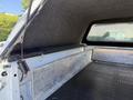 A white 2014 Ford F-250 SD truck bed with a soft cover and a metal divider in the foreground