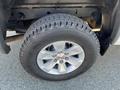 A close-up of a silver GMC wheel with a rugged tire mounted on it showcasing the brand logo