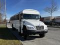 A 2022 Blue Bird Vision school bus with a white exterior and black wheels parked on a street