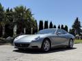 A silver 2005 Ferrari 612 Scaglietti is showcased in the foreground featuring a sleek design and distinctive curves with a low profile and prominent headlights