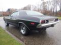 A 1974 Dodge Challenger in black with chrome accents and a sleek, muscular design showcasing its curved roofline and distinctive rear taillights