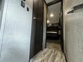 Interior view of a 2021 Grand Design Recreational 311BHS featuring a hallway leading to a bedroom area with a bed and dark wood cabinetry