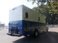 A blue and white 2008 Peterbilt PB340 with a boxy design featuring multiple compartments and a ladder on the back