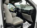 Interior of a 2016 Ford F-150 showing driver's side with light gray upholstery and spacious seating area featuring a center console and dashboard controls