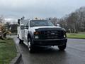 A white 2009 Ford F-550 with a utility body and emergency lights on the roof parked on a street