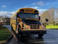 2005 Blue Bird 48 Passenger Bus with a yellow exterior and prominent black front features side mirrors and the words SCHOOL BUS on the front panel