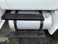 A 2011 International 4300 diesel fuel tank with black metal steps leading up to it and secured with black straps