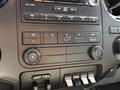 Interior controls of a 2015 Ford F-550 featuring dials for air conditioning fan speed and temperature along with buttons for various settings and auxiliary functions