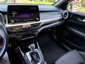 Interior view of a 2024 Kia Forte5 showcasing the dashboard touchscreen controls air conditioning knobs and gear shift lever