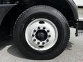 Close-up of a large truck tire and wheel assembly with a black wall tire and a white multi-stud rim designed for heavy-duty vehicles