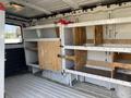 Interior of a 2012 GMC Savana van featuring wooden shelving units on both sides with metal brackets and a bare floor