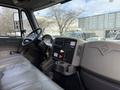 Interior of a 2011 International 4300 featuring a driver seat dashboard controls and gear shifter in a cab without passengers